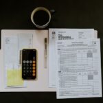 Tax - black Android smartphone near ballpoint pen, tax withholding certificate on top of white folder