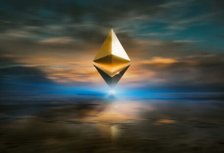 Crypto - yellow and black triangular structure under cloudy sky during sunset